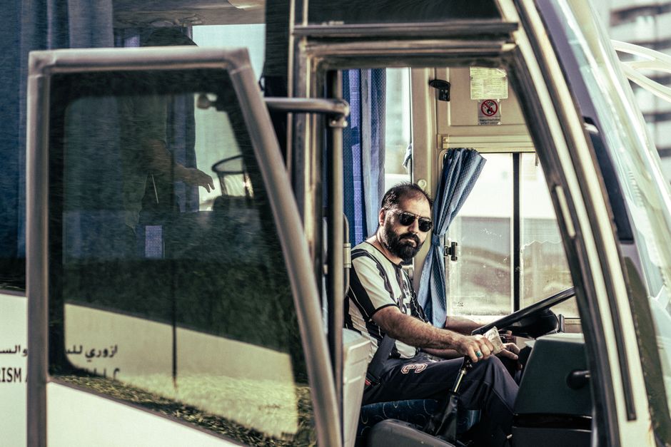 Een buschauffeur van EBS in uniform, die een bus bestuurt in een stedelijke omgeving, met focus op professionele groei.